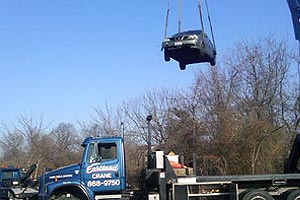 Lifting a vehicle out of a water retention pond in the woods using a crane.